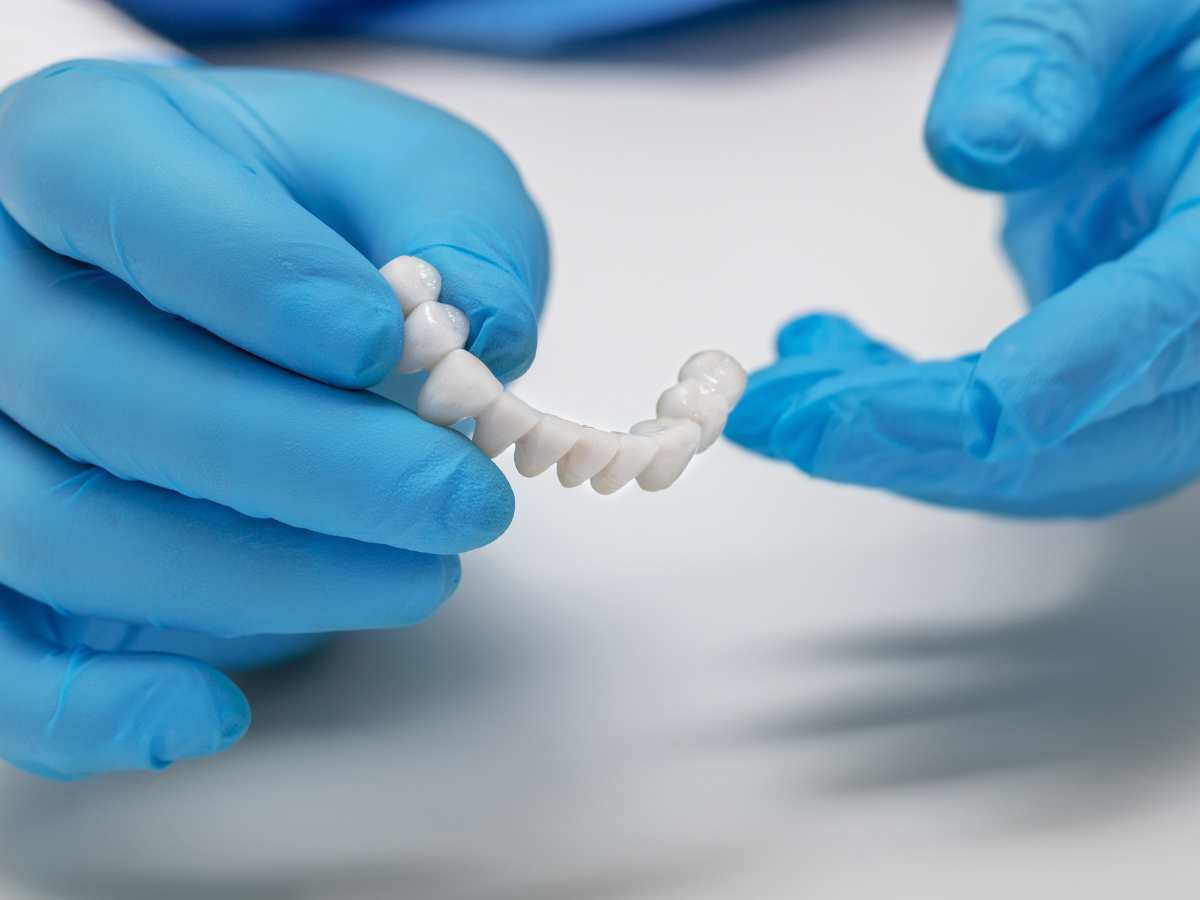 Dental professional holding a dental bridge model, demonstrating restorative dentistry solutions at Harborside Dental, Gloucester, MA.
