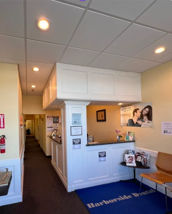 Dental office reception area at Harborside Dental, featuring a welcoming front desk, informational brochures, and a blue mat with the practice's name, emphasizing a family-friendly atmosphere in Gloucester, MA.