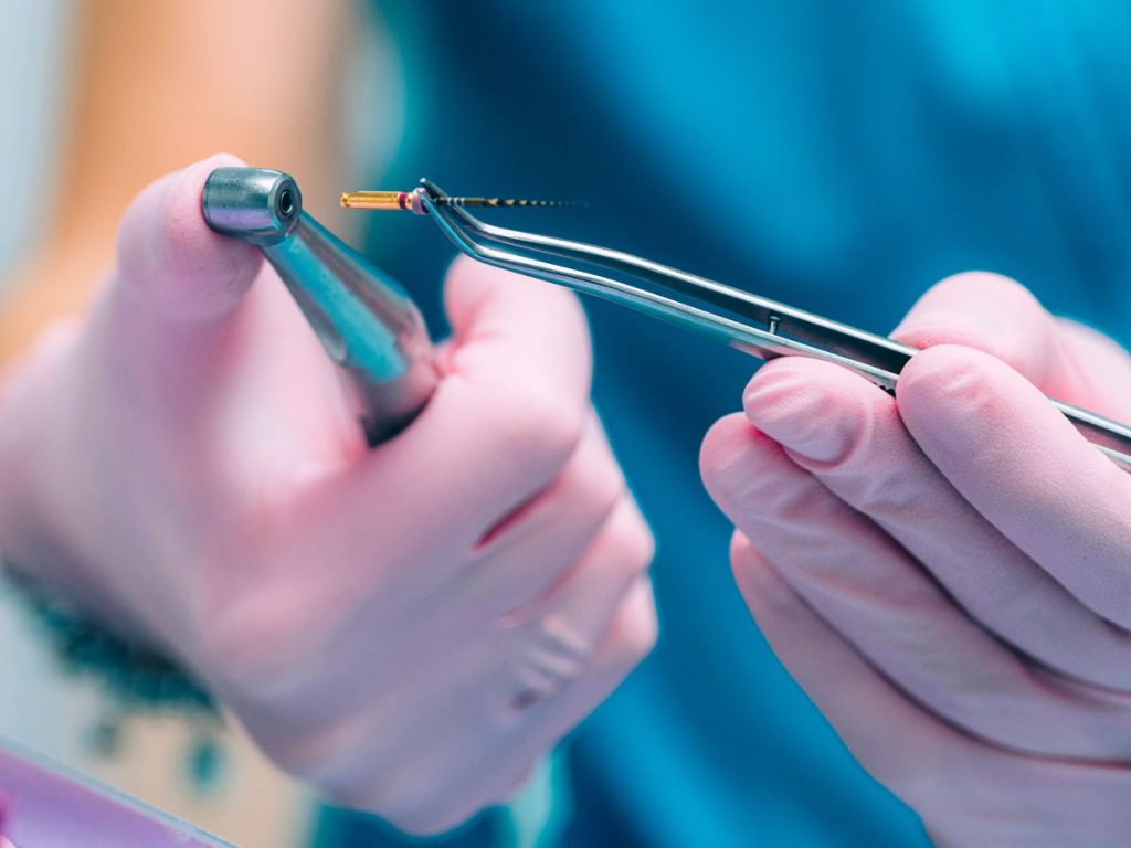 Dentist holding endodontic instruments during a root canal procedure